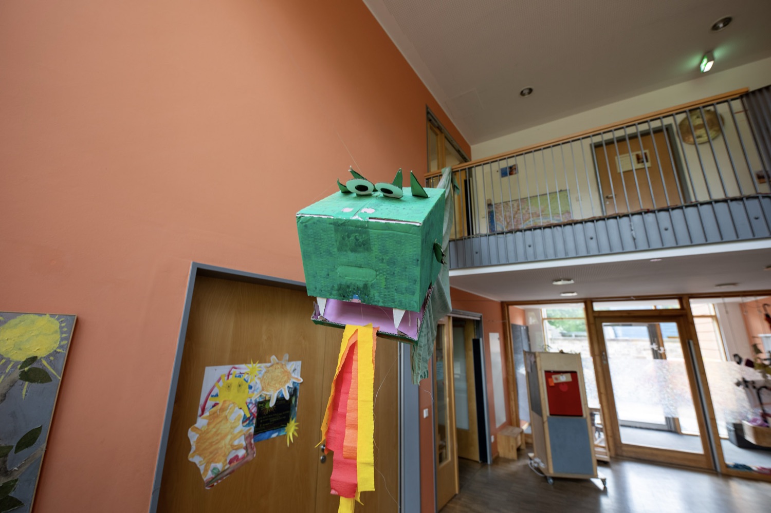 Offener, zweigeschossiger Eingangsbereich im Erdgeschoss mit Galerie und einem von Kindern gebastelten Drachen