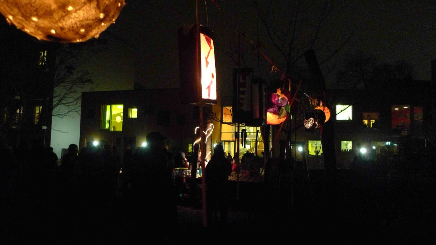 Laternenfest am Abend mit selbst gebastelten Laternen vor dem beleuchteten Kinderhaus
